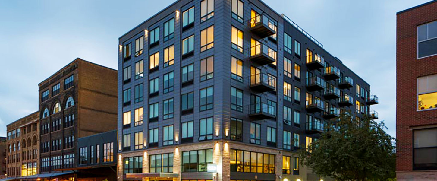 A multi-story apartment building at dusk fitted with Quaker commercial windows