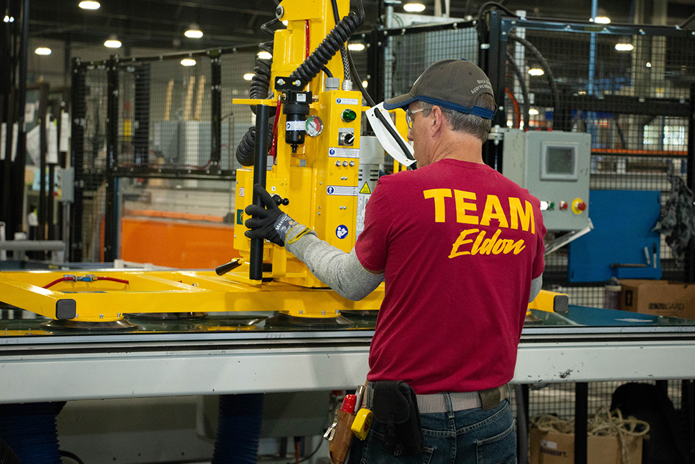 A Quaker team member operating a glass-handling lift on the Eldon production line