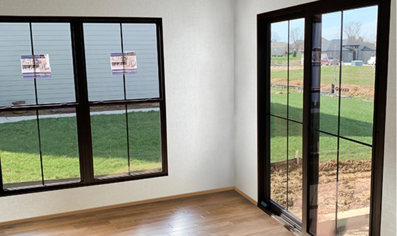 A newly installed Quaker window and patio door, factory labels still on the glass